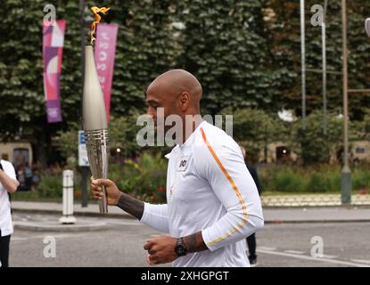 Paris, France. 14 juillet 2024. Thierry Henry, entraîneur des Jeux Olympiques de football français 2024, tient la flamme olympique lors du relais de la flamme des Jeux Olympiques Paris 2024 à Paris, France, le 14 juillet 2024. Crédit : Gao Jing/Xinhua/Alamy Live News Banque D'Images