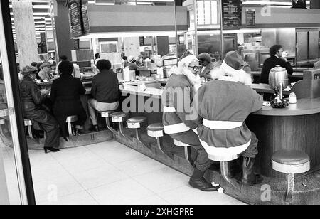 New York, NY, 1976 : dans une épicerie fine à Manhaten, un couple de Santa Claus de l'Armée du Salut prennent une pause en se tenant le long des trottoirs pour demander des dons aux acheteurs. Banque D'Images