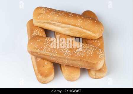 Pile de brioches brunes hotdog avec des graines de sésame isolées sur fond blanc de studio Banque D'Images