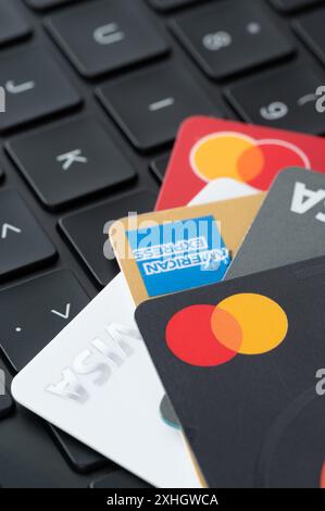 New York, États-Unis - 5 juillet 2024 : différentes cartes bancaires en plastique visa, mastercard et american Express sur clavier noir d'ordinateur portable Banque D'Images