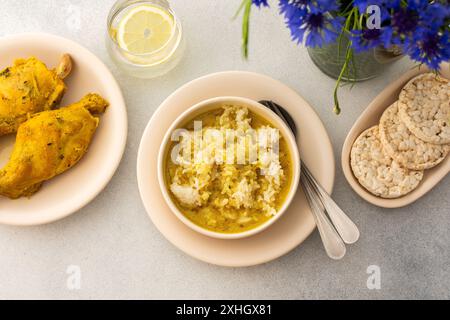 Ragoût de lapin avec du riz, du brocoli et des gâteaux de riz, une table servie avec de la nourriture et un vase de fleurs, un délicieux déjeuner copieux ou dîner Banque D'Images