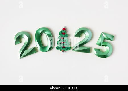 Jouet tricoté pour arbre de Noël et numéros verts. Le symbole de l'année 2025 sur fond gris. Banque D'Images