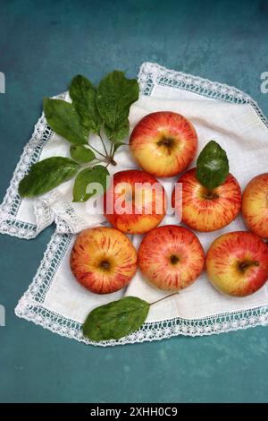 Pommes sur une serviette blanche sur un fond turquoise avec espace pour le texte. Composition simple Still Life avec pomme rouge. Banque D'Images