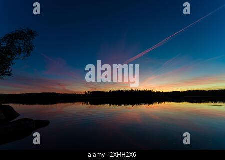 Un beau coucher de soleil peint des couleurs vives du ciel et des reflets sur un lac serein, entouré par la nature tranquillité Banque D'Images