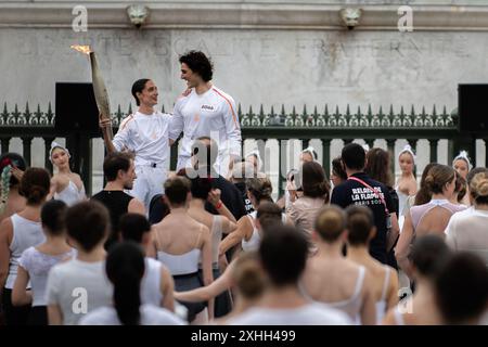 14 juillet 2024, Paris, France. Les porteurs de la torche posent parmi les danseurs alors que la torche olympique traverse la place de la Bastille, en traversant Paris. Crédit : Jay Kogler/Alamy Live News Banque D'Images