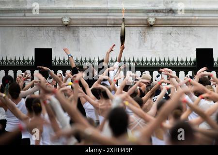 14 juillet 2024, Paris, France. Les porteurs de la torche exécutent une danse alors que la torche olympique traverse la place de la Bastille, en traversant Paris. Crédit : Jay Kogler/Alamy Live News Banque D'Images