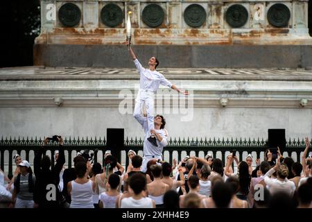 14 juillet 2024, Paris, France. Les porteurs de la torche exécutent une danse alors que la torche olympique traverse la place de la Bastille, en traversant Paris. Crédit : Jay Kogler/Alamy Live News Banque D'Images