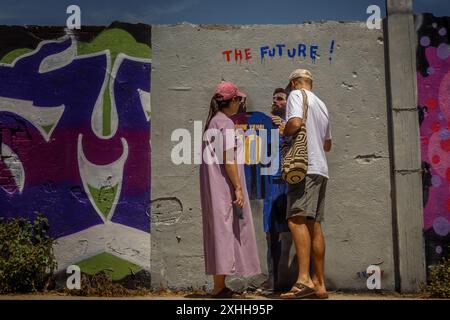 Barcelone, Espagne. 14 juin 2024. Les navetteurs inspectent la nouvelle murale de l'artiste urbain italien 'TVBoy', Salvatore Benintende. Intitulé « The future », le graffiti représente Lionel Messi portant un maillot du FC Barcelone avec son ancien numéro 10 et le nom Lamine Yamal, présentant la jeune star le jour où il pourrait devenir le plus jeune vainqueur d'un championnat de l'UEFA Euro, en tant que successeur. Crédit : Matthias Oesterle/Alamy Live News Banque D'Images