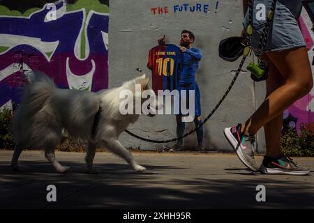 Barcelone, Espagne. 14 juin 2024. Un voyageur passe devant une murale de l'artiste urbain italien 'TVBoy', Salvatore Benintende. Intitulé « The future », le graffiti représente Lionel Messi portant un maillot du FC Barcelone avec son ancien numéro 10 et le nom Lamine Yamal, présentant la jeune star le jour où il pourrait devenir le plus jeune vainqueur d'un championnat de l'UEFA Euro, en tant que successeur. Crédit : Matthias Oesterle/Alamy Live News Banque D'Images