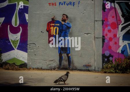 Barcelone, Espagne. 14 juin 2024. Une colombe passe devant une murale de l'artiste urbain italien 'TVBoy', Salvatore Benintende. Intitulé « The future », le graffiti représente Lionel Messi portant un maillot du FC Barcelone avec son ancien numéro 10 et le nom Lamine Yamal, présentant la jeune star le jour où il pourrait devenir le plus jeune vainqueur d'un championnat de l'UEFA Euro, en tant que successeur. Crédit : Matthias Oesterle/Alamy Live News Banque D'Images