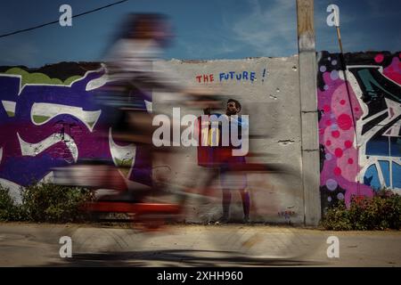 Barcelone, Espagne. 14 juin 2024. Un voyageur passe devant une murale de l'artiste urbain italien 'TVBoy', Salvatore Benintende. Intitulé « The future », le graffiti représente Lionel Messi portant un maillot du FC Barcelone avec son ancien numéro 10 et le nom Lamine Yamal, présentant la jeune star le jour où il pourrait devenir le plus jeune vainqueur d'un championnat de l'UEFA Euro, en tant que successeur. Crédit : Matthias Oesterle/Alamy Live News Banque D'Images