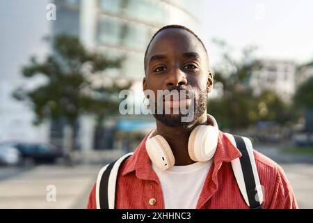 Jeune homme africain souriant debout dans la rue de la ville regardant la caméra. Portrait Banque D'Images