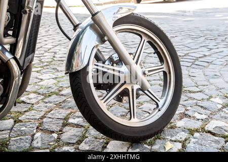 Gros plan de la roue avant d'une moto classique garée dans la rue Banque D'Images