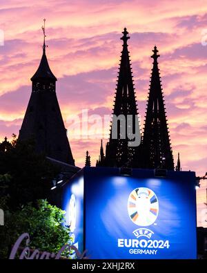 Public Viewing in Köln Fan-zone am Heumarkt Köln 14.07.2024 Blick auf Kölner Dom, Sonnenuntergang, logo von UEFA EURO 2024 auf dem Schild neben Eingang. Visite publique à Köln Fan-zone am Heumarkt Köln 14.07.2024 Köln Heumarkt NRW Deutschland *** visite publique à Cologne Fan-zone à Heumarkt Cologne 14 07 2024 vue de la cathédrale de Cologne, coucher de soleil, logo UEFA EURO 2024 sur le panneau à côté de l'entrée public visionnement dans la zone des fans de Cologne au Heumarkt Cologne 14 07 2024 Cologne Heumarkt NRW Allemagne Copyright : xBEAUTIFULxSPORTS/Buriakovx Banque D'Images