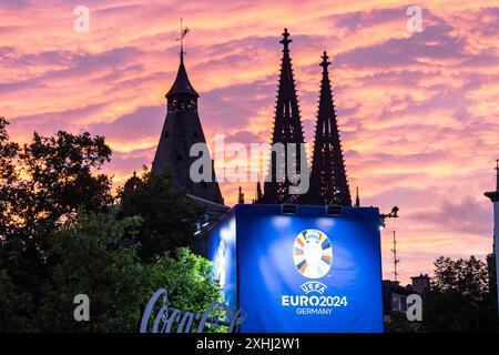 Public Viewing in Köln Fan-zone am Heumarkt Köln 14.07.2024 Blick auf Kölner Dom, Sonnenuntergang, logo von UEFA EURO 2024 auf dem Schild neben Eingang. Visite publique à Köln Fan-zone am Heumarkt Köln 14.07.2024 Köln Heumarkt NRW Deutschland *** visite publique à Cologne Fan-zone à Heumarkt Cologne 14 07 2024 vue de la cathédrale de Cologne, coucher de soleil, logo UEFA EURO 2024 sur le panneau à côté de l'entrée public visionnement dans la zone des fans de Cologne au Heumarkt Cologne 14 07 2024 Cologne Heumarkt NRW Allemagne Copyright : xBEAUTIFULxSPORTS/Buriakovx Banque D'Images