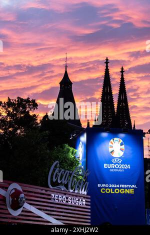 Public Viewing in Köln Fan-zone am Heumarkt Köln 14.07.2024 Blick auf Kölner Dom, Sonnenuntergang, logo von UEFA EURO 2024 auf dem Schild neben Eingang. Visite publique à Köln Fan-zone am Heumarkt Köln 14.07.2024 Köln Heumarkt NRW Deutschland *** visite publique à Cologne Fan-zone à Heumarkt Cologne 14 07 2024 vue de la cathédrale de Cologne, coucher de soleil, logo UEFA EURO 2024 sur le panneau à côté de l'entrée public visionnement dans la zone des fans de Cologne au Heumarkt Cologne 14 07 2024 Cologne Heumarkt NRW Allemagne Copyright : xBEAUTIFULxSPORTS/Buriakovx Banque D'Images