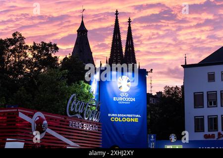 Public Viewing in Köln Fan-zone am Heumarkt Köln 14.07.2024 Blick auf Kölner Dom, Sonnenuntergang, logo von UEFA EURO 2024 auf dem Schild neben Eingang. Visite publique à Köln Fan-zone am Heumarkt Köln 14.07.2024 Köln Heumarkt NRW Deutschland *** visite publique à Cologne Fan-zone à Heumarkt Cologne 14 07 2024 vue de la cathédrale de Cologne, coucher de soleil, logo UEFA EURO 2024 sur le panneau à côté de l'entrée public visionnement dans la zone des fans de Cologne au Heumarkt Cologne 14 07 2024 Cologne Heumarkt NRW Allemagne Copyright : xBEAUTIFULxSPORTS/Buriakovx Banque D'Images