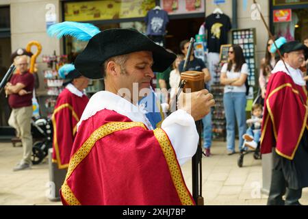 Astorga, Espagne - 4 juin 2023 : un homme en costume traditionnel rouge et or, tenant un long bâton, participe à une procession festive à travers la str Banque D'Images