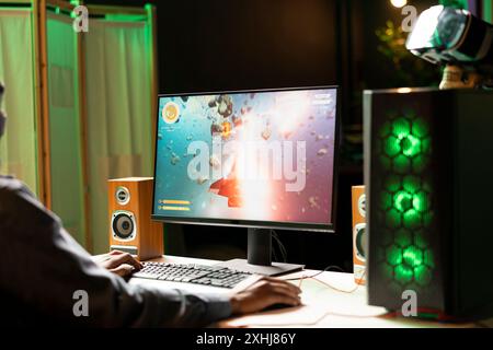 Joueur dans l'appartement éclairé au néon maison tirant des météorites dans le vaisseau spatial volant jeu solo sur ordinateur de bureau. Joueur naviguant dans la galaxie, exploser des ennemis dans le jeu de simulation sur PC de jeu Banque D'Images