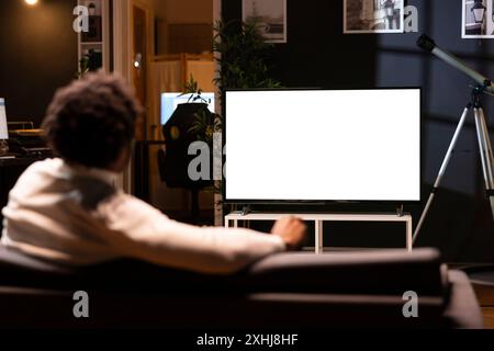 Personne utilisant la télévision à écran isolé pour lier des séries sur des services de streaming basés sur abonnement. Coupe-cordon relaxant sur le canapé, profiter de la vidéo à la demande sur la télévision maquette Banque D'Images