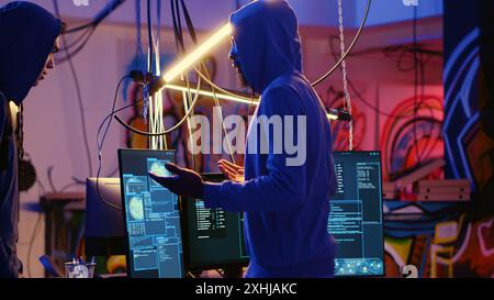 Chef de groupe de pirates informatiques voyous accueillant un nouveau membre dans une base souterraine cachée, prêt à lui apprendre comment passer les mesures anti-sabotage mises en œuvre par les entreprises pour protéger leurs produits Banque D'Images