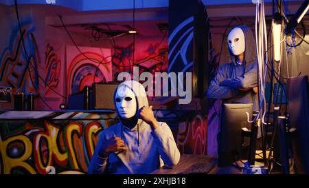 Des membres de groupes de pirates informatiques commettent des actes de terrorisme en ligne, filment des vidéos de rançon avec un smartphone dans une base souterraine cachée, menaçant de divulguer publiquement des données sensibles volées si les demandes de paiement ne sont pas satisfaites Banque D'Images