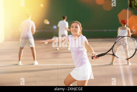 Femme servant le ballon pendant le jeu frontenis à l'extérieur Banque D'Images