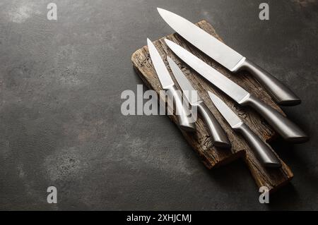 Acier coulant divers couteaux de chef, ensemble de couteaux de cuisine modernes pointus sur fond sombre Banque D'Images