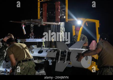 Les marins de l'US Navy affectés au Helicopter Sea combat Squadron (HSC) 21 et au HSC-23, Naval Air Station North Island, San Diego, chargent un système aéroporté de neutralisation des mines sur un MH-60S Seahawk lors de l'exercice Rim of the Pacific (RIMPAC) 2024, Hawaï, le 12 juillet. Vingt-neuf pays, 40 navires de surface, trois sous-marins, 14 forces terrestres nationales, plus de 150 avions et 25 000 membres du personnel participent au RIMPAC dans et autour des îles Hawaï, du 27 juin au 1er août. Le RIMPAC, le plus grand exercice maritime international au monde, offre une occasion unique de formation tout en favorisant et en soutenant la coopération Banque D'Images