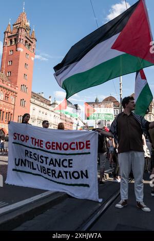 Bâle, Suisse. 13 juillet 2024. Les partisans de la Palestine tiennent une bannière et des drapeaux pendant le rassemblement. Des dizaines de personnes ont défilé dans les rues de Bâle pour une manifestation spontanée et non autorisée en faveur de la Palestine. Brandissant des drapeaux et chantant des slogans célèbres comme « de la rivière à la mer », la procession a commencé à BarfÃ¼serplatz et a fait une tournée d'une heure et demie à travers la ville. (Crédit image : © Matteo Placucci/SOPA images via ZUMA Press Wire) USAGE ÉDITORIAL SEULEMENT! Non destiné à UN USAGE commercial ! Banque D'Images