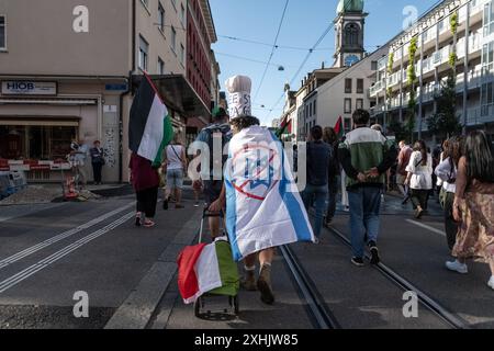 Bâle, Suisse. 13 juillet 2024. Les partisans de la Palestine défilent dans les rues de la ville pendant le rassemblement. Des dizaines de personnes ont défilé dans les rues de Bâle pour une manifestation spontanée et non autorisée en faveur de la Palestine. Brandissant des drapeaux et chantant des slogans célèbres comme « de la rivière à la mer », la procession a commencé à BarfÃ¼serplatz et a fait une tournée d'une heure et demie à travers la ville. (Crédit image : © Matteo Placucci/SOPA images via ZUMA Press Wire) USAGE ÉDITORIAL SEULEMENT! Non destiné à UN USAGE commercial ! Banque D'Images