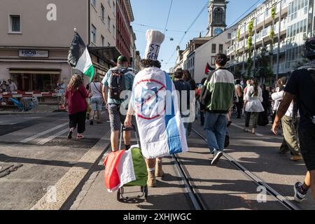 Bâle, Suisse. 13 juillet 2024. Les partisans de la Palestine défilent dans les rues de la ville pendant le rassemblement. Des dizaines de personnes ont défilé dans les rues de Bâle pour une manifestation spontanée et non autorisée en faveur de la Palestine. Brandissant des drapeaux et chantant les fameux slogans comme « de la rivière à la mer », la procession a commencé à Barfüserplatz et a fait une tournée d’une heure et demie à travers la ville. (Photo de Matteo Placucci/SOPA images/SIPA USA) crédit : SIPA USA/Alamy Live News Banque D'Images