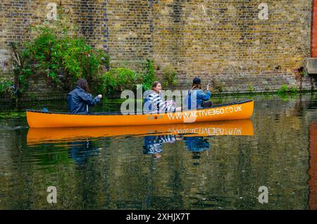 Trois personnes pagayent en canoë le long du Grand Union canal Paddington Arm à Londres, au Royaume-Uni Banque D'Images