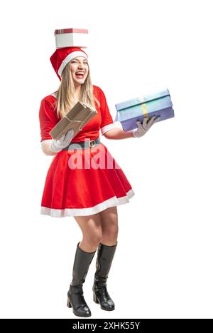 Drôle de femme latine habillée comme le Père Noël en équilibre avec divers cadeaux isolés sur fond blanc Banque D'Images