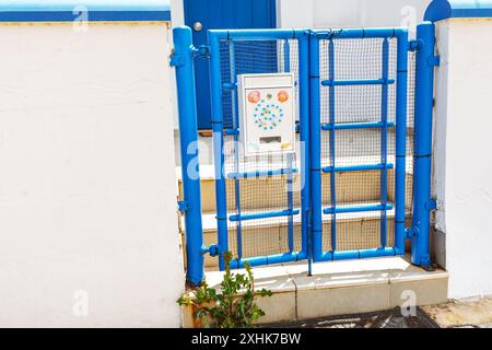 Portail bleu avec boîte aux lettres décorée et mur blanc. La porte est fermée et il y a une boîte aux lettres sur le mur Banque D'Images