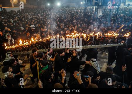 Najaf, Irak. 14 juillet 2024. Les musulmans chiites effectuent des rituels de deuil lors d'une procession religieuse avant le jour de l'Ashura, le dixième jour du mois sacré de Muharram. Ashura commémore le martyre de l'imam Hussein, petit-fils du prophète de l'islam Mohammed, dans la bataille de la ville irakienne de Karbala au VIIe siècle. Crédit : Ismael Adnan/dpa/Alamy Live News Banque D'Images