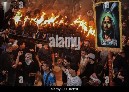 Najaf, Irak. 14 juillet 2024. Les musulmans chiites effectuent des rituels de deuil lors d'une procession religieuse avant le jour de l'Ashura, le dixième jour du mois sacré de Muharram. Ashura commémore le martyre de l'imam Hussein, petit-fils du prophète de l'islam Mohammed, dans la bataille de la ville irakienne de Karbala au VIIe siècle. Crédit : Ismael Adnan/dpa/Alamy Live News Banque D'Images