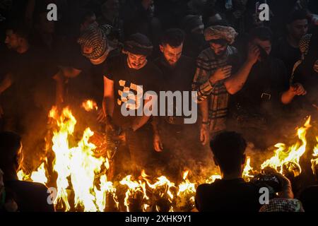 Najaf, Irak. 14 juillet 2024. Les musulmans chiites effectuent des rituels de deuil lors d'une procession religieuse avant le jour de l'Ashura, le dixième jour du mois sacré de Muharram. Ashura commémore le martyre de l'imam Hussein, petit-fils du prophète de l'islam Mohammed, dans la bataille de la ville irakienne de Karbala au VIIe siècle. Crédit : Ismael Adnan/dpa/Alamy Live News Banque D'Images