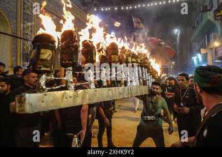 Najaf, Irak. 14 juillet 2024. Les musulmans chiites effectuent des rituels de deuil lors d'une procession religieuse avant le jour de l'Ashura, le dixième jour du mois sacré de Muharram. Ashura commémore le martyre de l'imam Hussein, petit-fils du prophète de l'islam Mohammed, dans la bataille de la ville irakienne de Karbala au VIIe siècle. Crédit : Ismael Adnan/dpa/Alamy Live News Banque D'Images