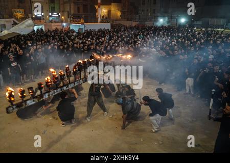 Najaf, Irak. 14 juillet 2024. Les musulmans chiites effectuent des rituels de deuil lors d'une procession religieuse avant le jour de l'Ashura, le dixième jour du mois sacré de Muharram. Ashura commémore le martyre de l'imam Hussein, petit-fils du prophète de l'islam Mohammed, dans la bataille de la ville irakienne de Karbala au VIIe siècle. Crédit : Ismael Adnan/dpa/Alamy Live News Banque D'Images