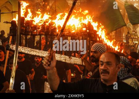 Najaf, Irak. 14 juillet 2024. Les musulmans chiites effectuent des rituels de deuil lors d'une procession religieuse avant le jour de l'Ashura, le dixième jour du mois sacré de Muharram. Ashura commémore le martyre de l'imam Hussein, petit-fils du prophète de l'islam Mohammed, dans la bataille de la ville irakienne de Karbala au VIIe siècle. Crédit : Ismael Adnan/dpa/Alamy Live News Banque D'Images