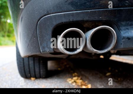 Hambourg, Allemagne. 15 juillet 2024. Un tuyau d'échappement est suspendu à une voiture. Le gouvernement allemand est à nouveau jugé pour sa politique environnementale et climatique. Crédit : Daniel Bockwoldt/dpa/Alamy Live News Banque D'Images