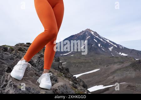 Vue avant de la partie basse des jambes du modèle de fitness en leggings de sport orange et baskets. Femme en forme faisant de l'entraînement de fitness en plein air tout en randonnée et tra Banque D'Images