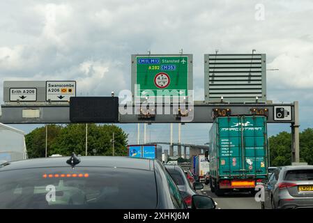 Files d'attente sur l'autoroute M25 en direction du tunnel de Dartford dans le Kent, Royaume-Uni. Congestion. Panneaux de destination pour Erith, Swanscombe, Stansted Banque D'Images