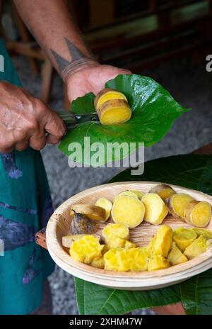 Polynésie française, île de Tahiti, patate douce polynésienne tatouée coupée avec un couteau sur une feuille et la servir sur une assiette Banque D'Images