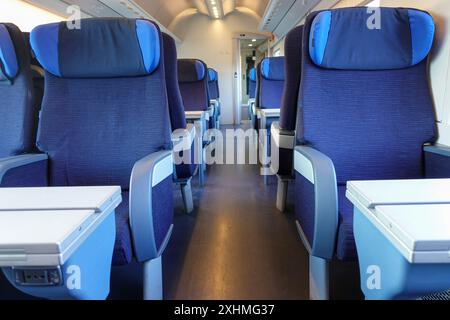 Rangées de sièges bleus vides avec appuie-tête et tables pliantes à l'intérieur d'un train à grande vitesse moderne Banque D'Images