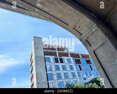 Bâtiment moderne en verre en construction encadré par une arche en béton Banque D'Images