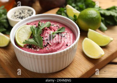 Savoureux houmous de betterave avec citron vert et persil dans un bol sur une table en bois, gros plan Banque D'Images