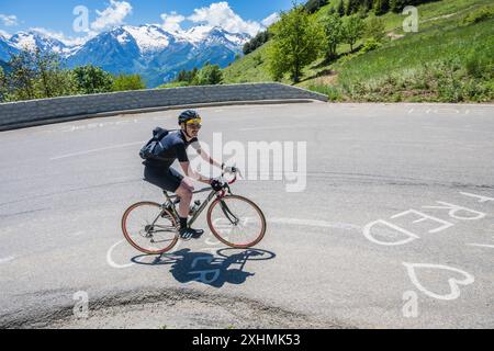 Un cycliste de route masculin chevauchant la célèbre Alpe d'Huez grimpe dans les Alpes françaises. C'est le virage 3 et connu comme un point de vue spécial sur la montée. Banque D'Images