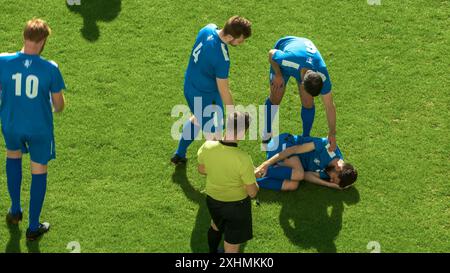 Football Football Championship match : L'arbitre voit faute, donne signal et carton jaune, vérifie le joueur blessé sur le terrain. Tournoi international. Sport Broadcast Channel concept de télévision. Banque D'Images